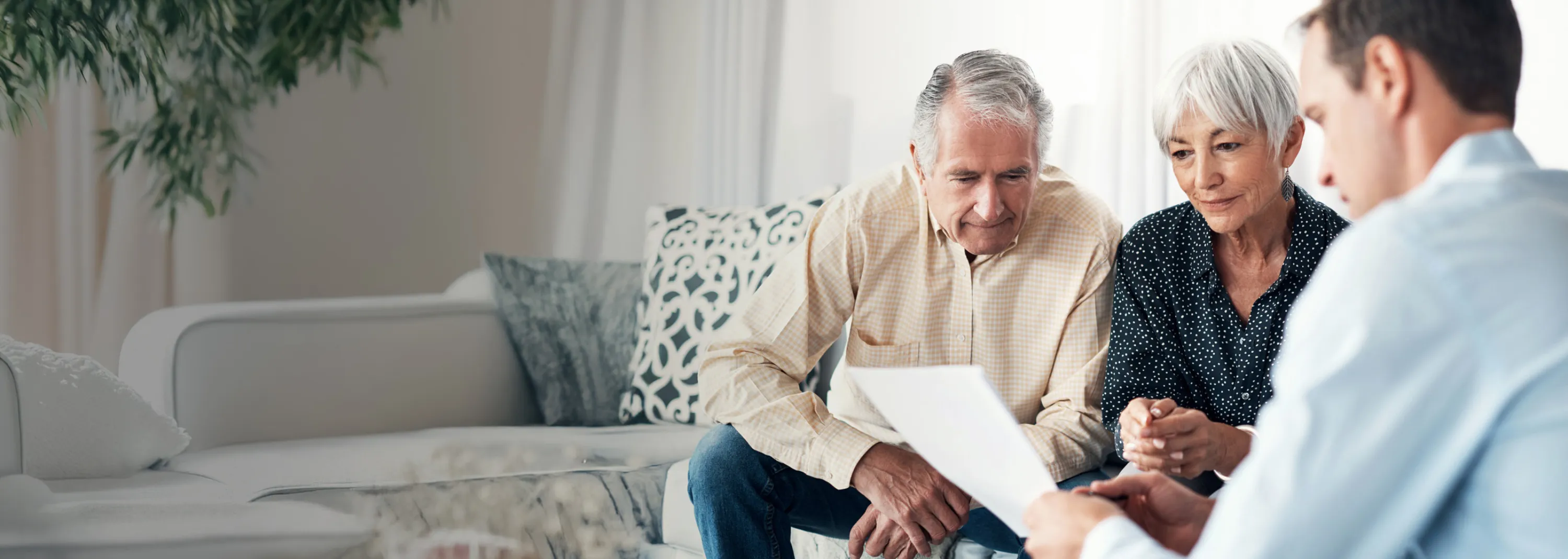Ein Paar und ein Notar sitzen auf einer Couch und schauen sich das Testament an.