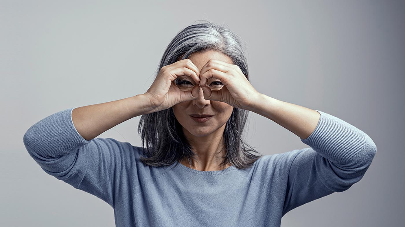 Eine Frau hält ihre Hände wie ein Fernglas über die Augen.