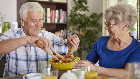 Una coppia di anziani: lei tiene l'insalatiera, lui si mescola l'insalata.