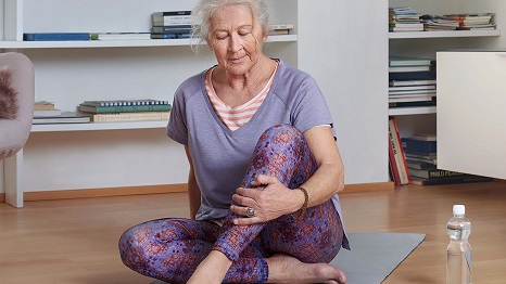 Signora anziana su un tappetino da yoga che fa esercizi di stretching 